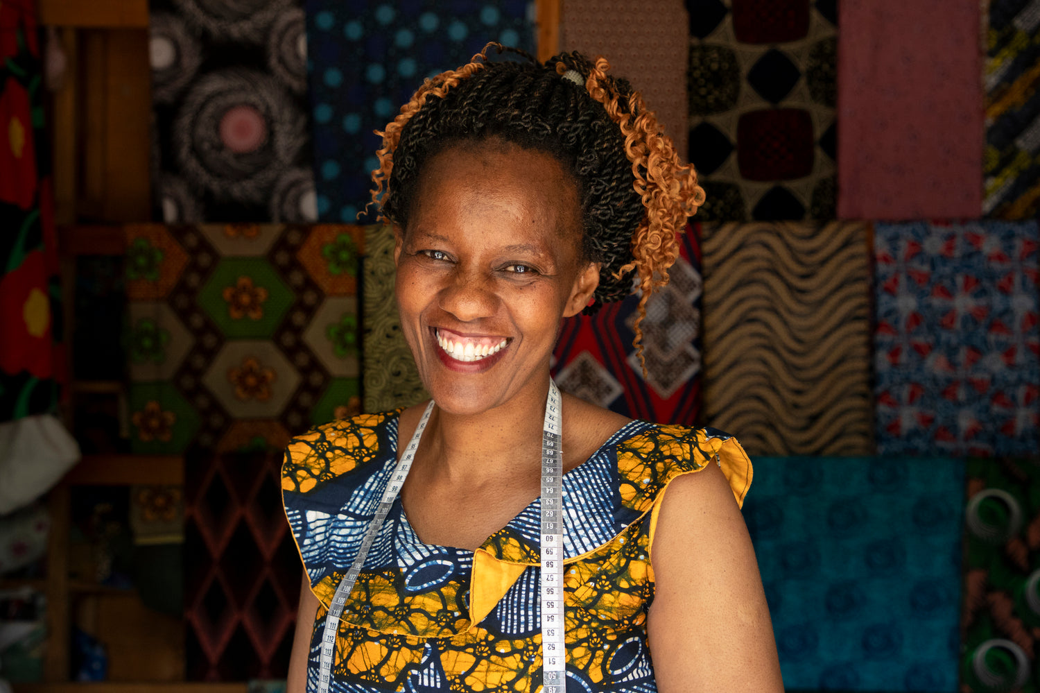 Sophie, a Tanzania woman and seamstress, smiles inside her shop.